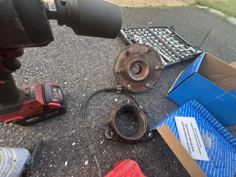 Removed wheel-hub components beside tools and parts packaging.