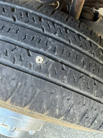 Close-up of a screw embedded in the tire tread.