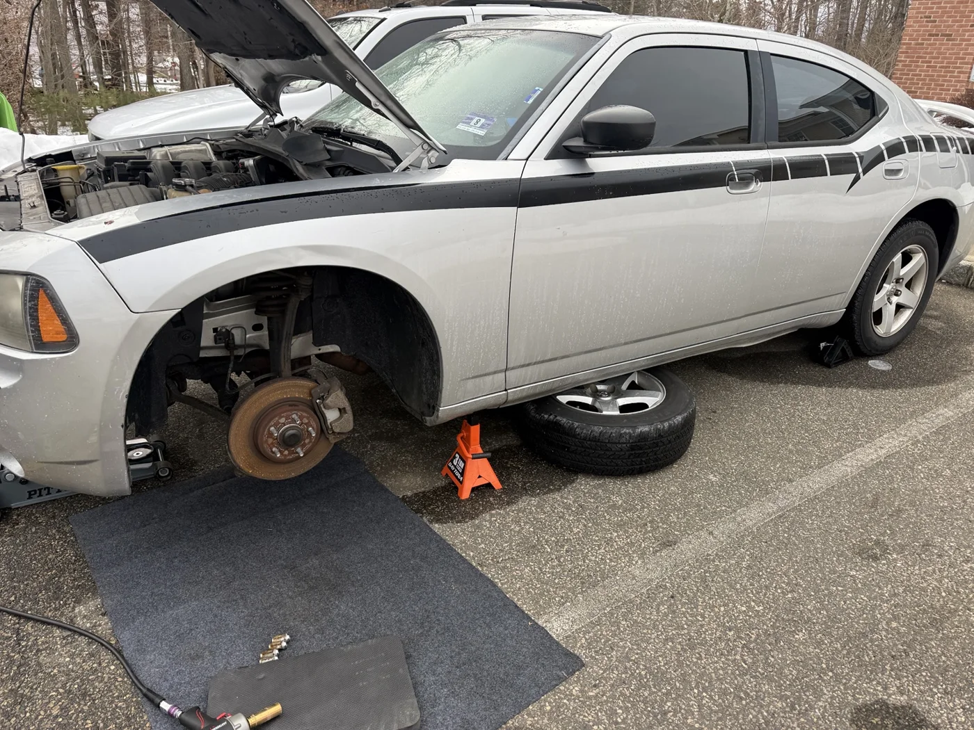 AMS work area beside a silver sedan with a front wheel removed